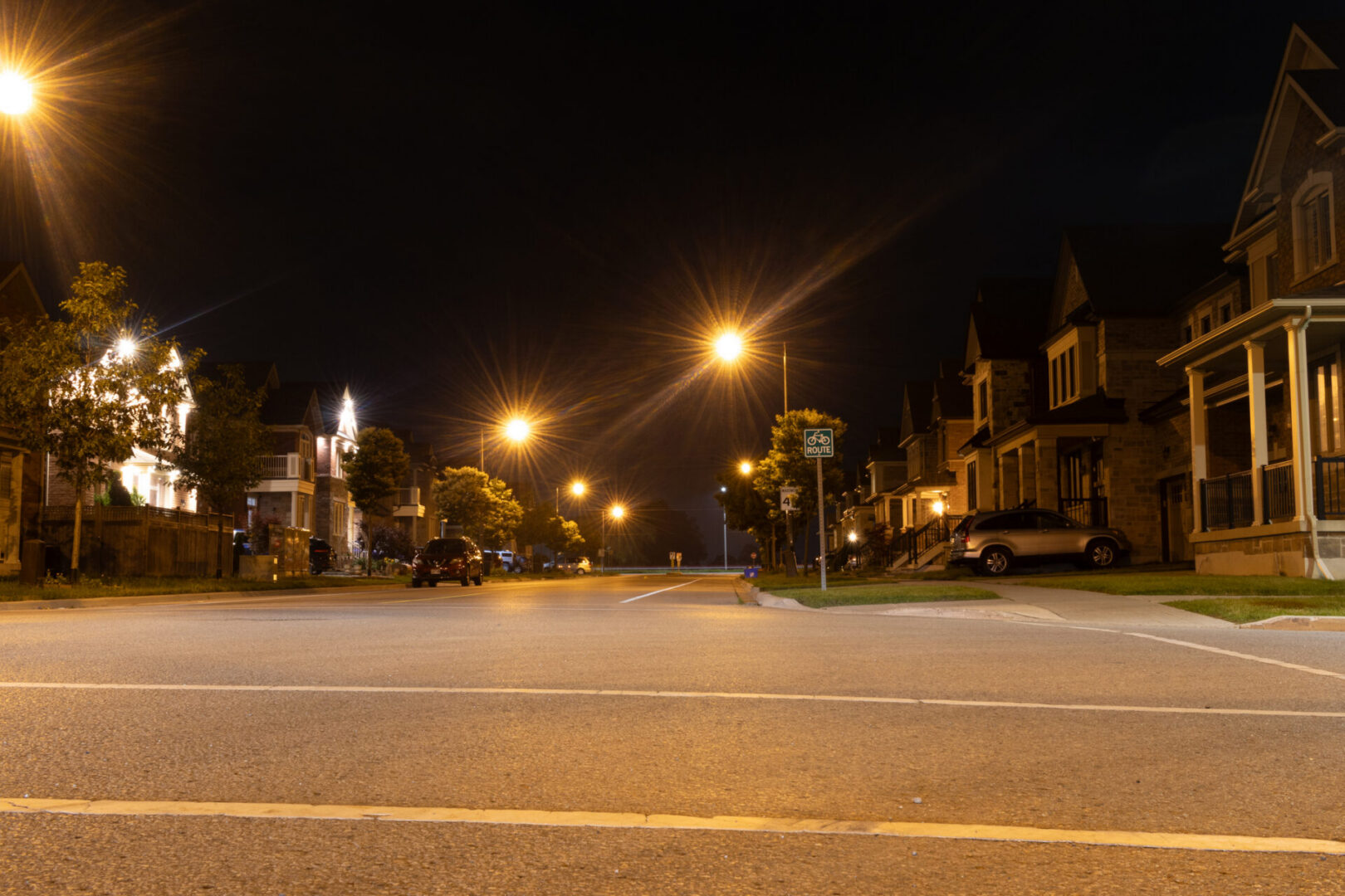Quiet residential street at night with lights.